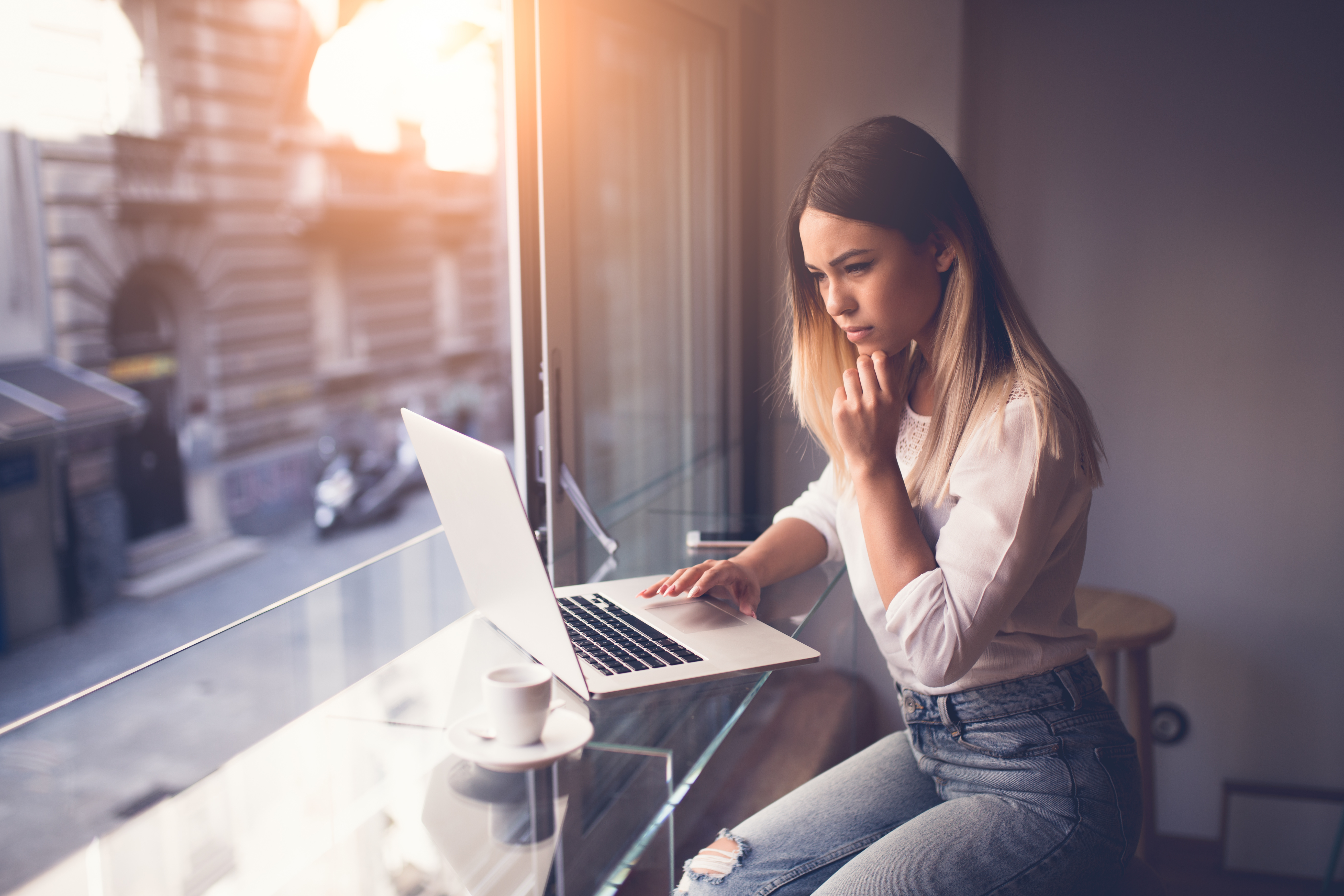Young woman siting at cafe drinking coffee and working on laptop
