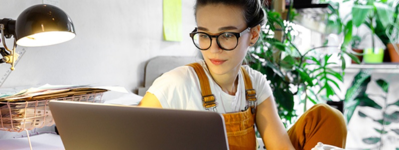 Woman wearing glasses while looking at her laptop screen.