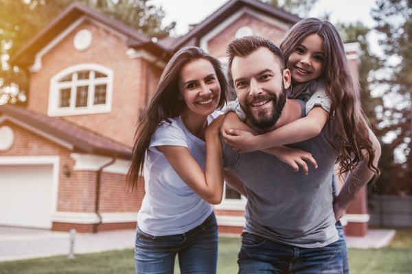 Family smiling in front of house