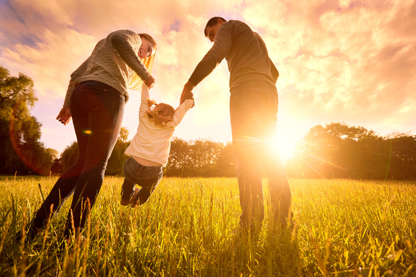 Family with child in field with sun in background