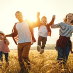 family walking through field laughing, lifting children