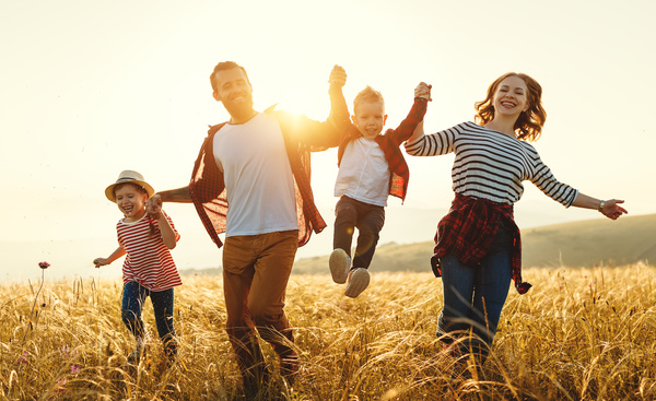 family walking through field laughing, lifting children