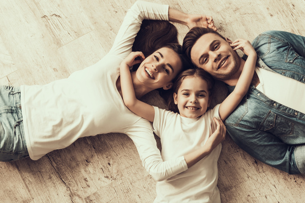 Family laying on backs on floor smiling at camera