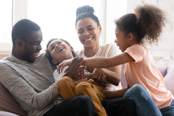 Family laughing and tickling on sofa