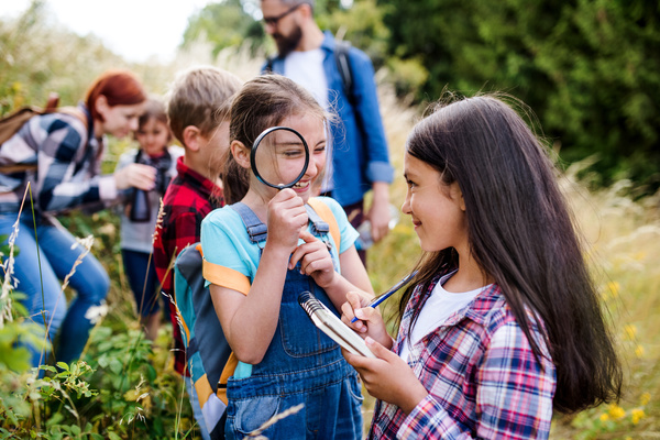 Kids out in a field exploring with magnifying glass