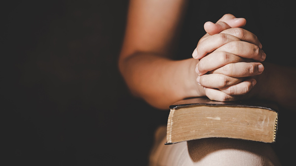 hands crossed sitting on bible