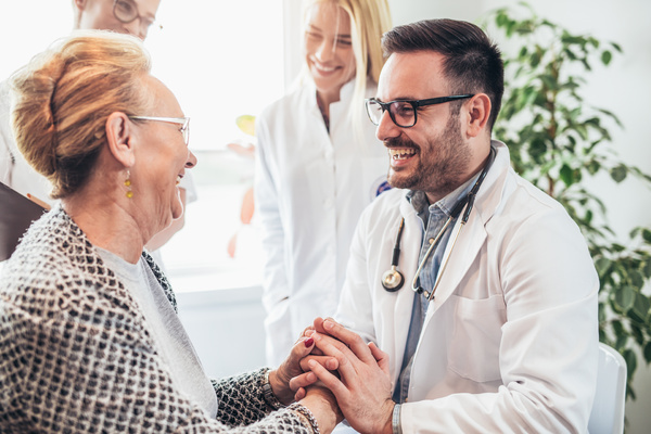 Doctor holding hands and smiling with older patient